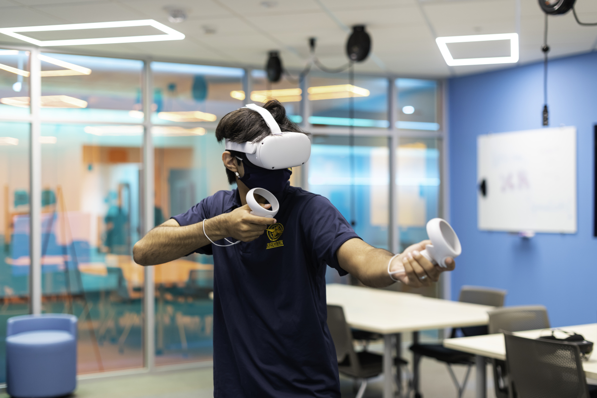 A Rochester student using the Meta Quest 2. His arms are positioned like he's holding a rifle