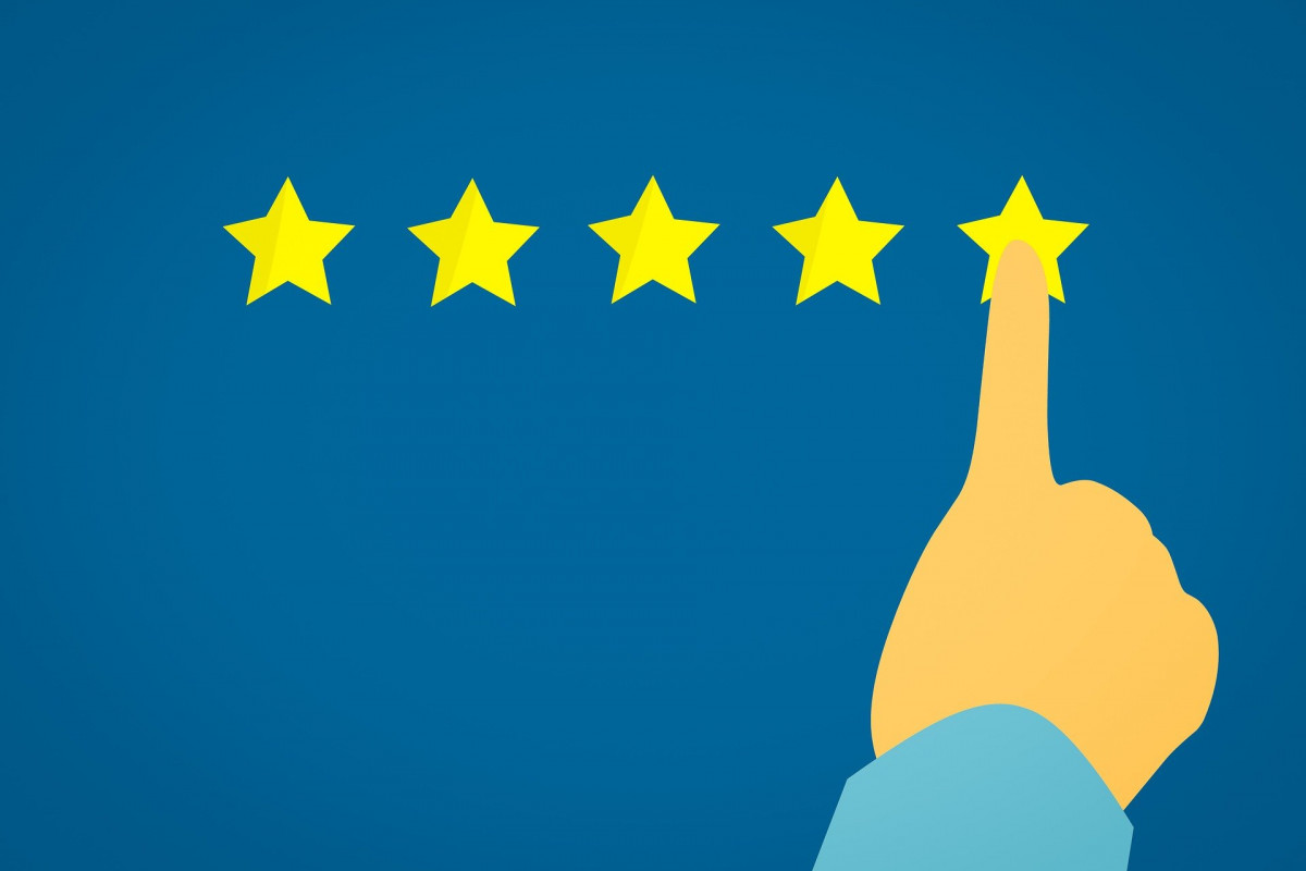 Five gold stars in a row with a person's finger on the fifth in line, as if they're giving a rating