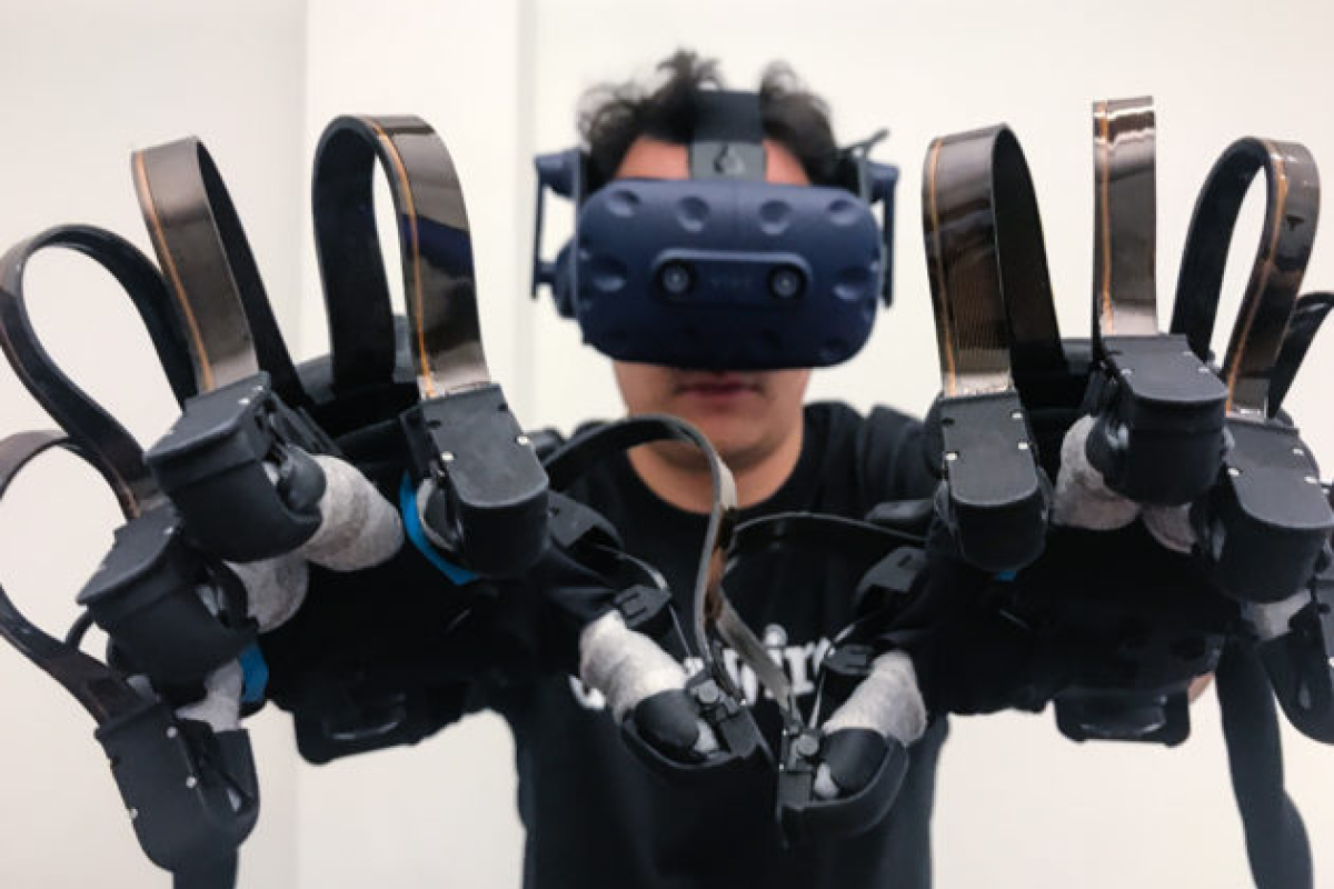 A person in a VR headset and haptic gloves engages with virtual reality.