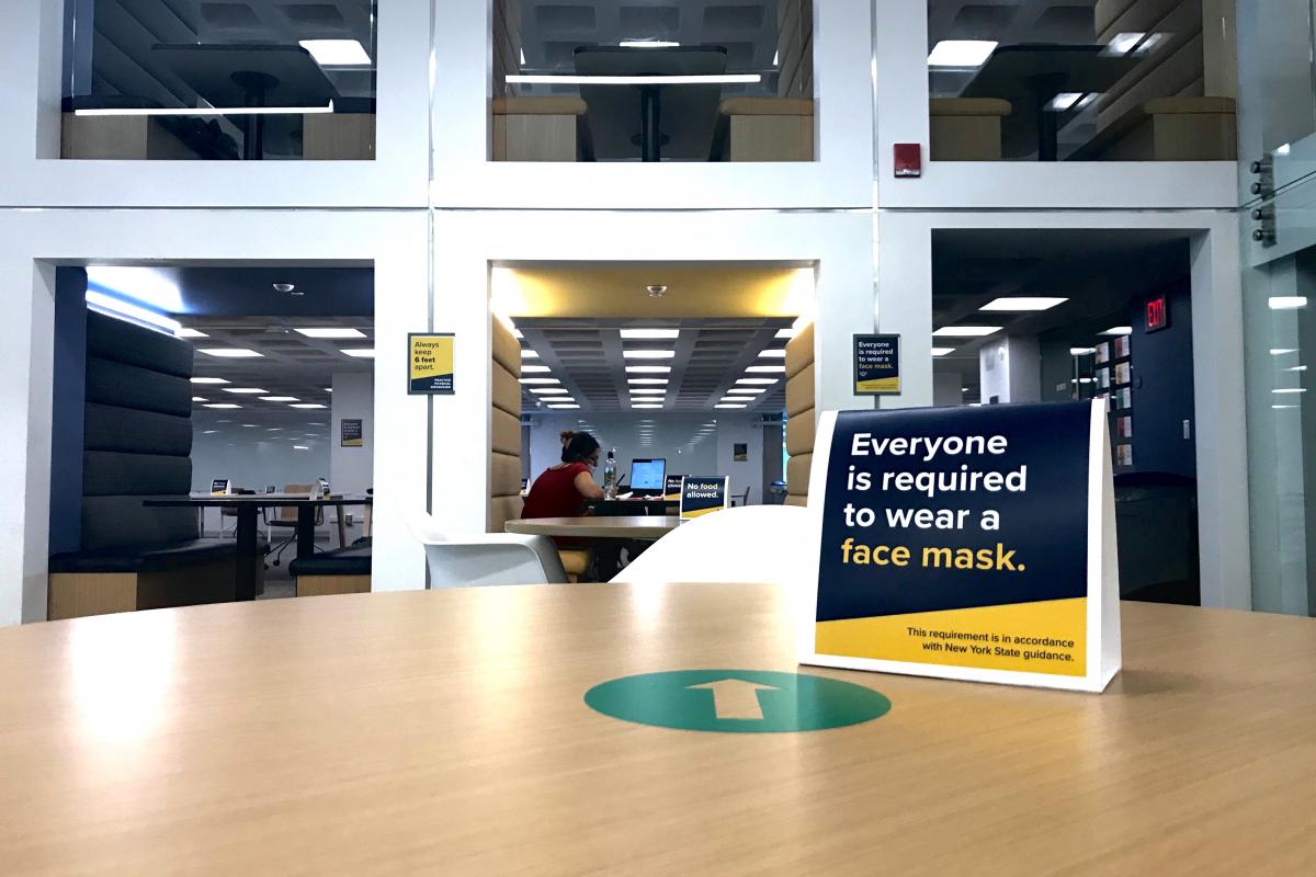 A view of iZone's booth seating and a COVID safety sign from the piazza