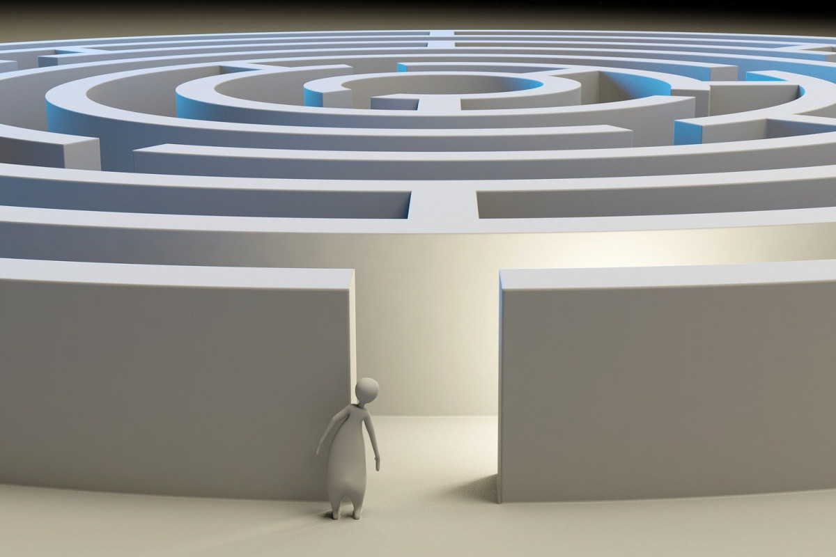 A human-looking figure at peering into the opening of a labyrinth