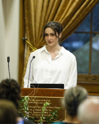 a portrait of Brenna Keef speaking at a lecturn