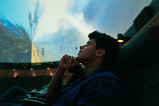student viewing a 360 video on the planetarium dome. 