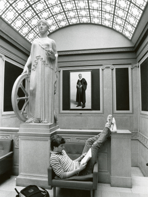 Photo of student sitting on bench next to statue